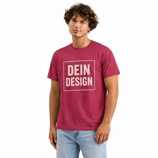 Mann trägt ein beerefarbenes T-Shirt, bedruckt mit dem Platzhalter-Schriftzug Dein Design in einem hellen quadratischen Rahmen.