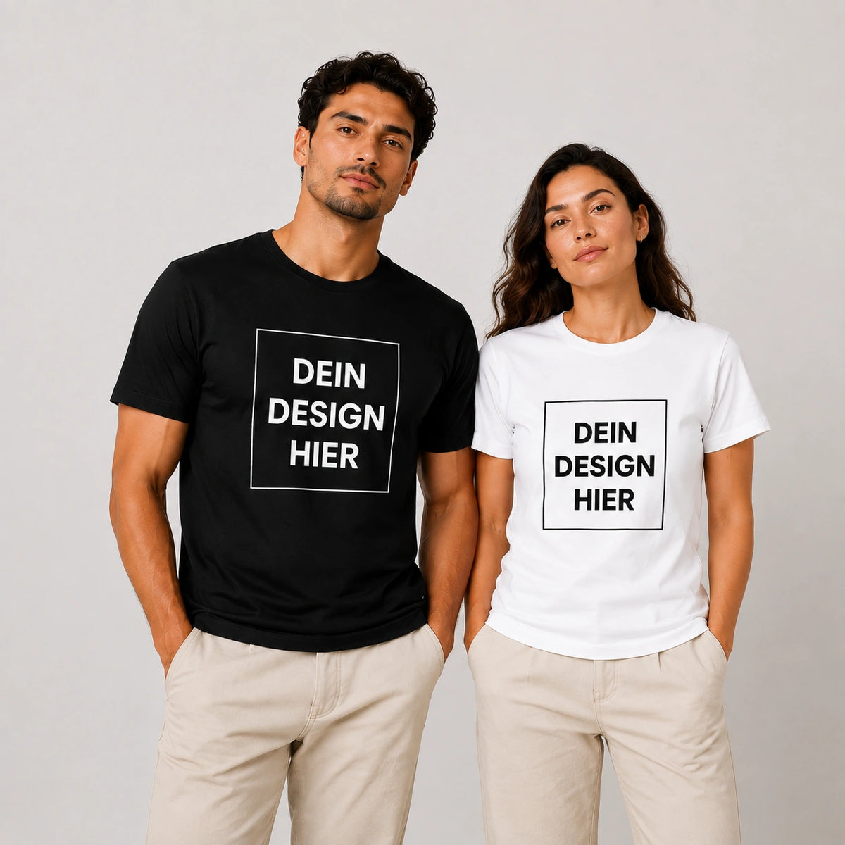 Ein Mann im schwarzen T-Shirt und eine Frau im weißen T-Shirt, beide bedruckt mit dem Platzhalter-Schriftzug Dein Design Hier.